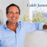 Caleb James Goddard smiling in a blue shirt against a bright Mediterranean background